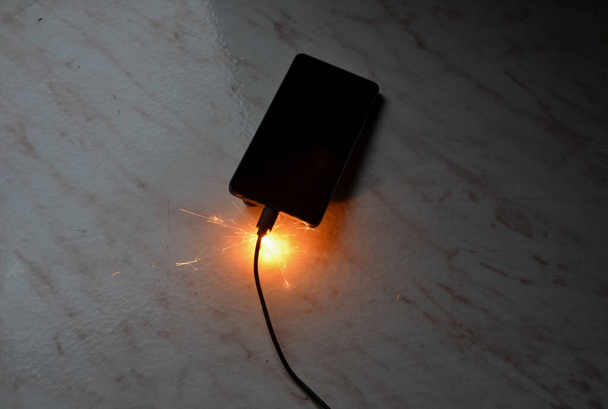 充電器に接続されています。一晩でバッテリーを充電しないとバッテリーが発火する危険性がある無人トランス。皮膚は電気源からの接続を切断し、財産を保存すると燃える - 写真・画像