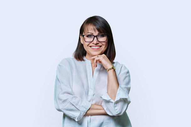 Portrait of beautiful smiling middle aged woman on white studio background. Mature attractive female in glasses with hairstyle make-up posing looking at camera. Beauty, 40s age, people concept - Photo, Image
