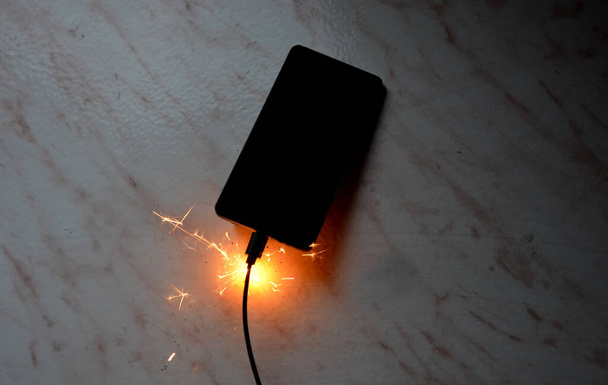 充電器に接続されています。一晩でバッテリーを充電しないとバッテリーが発火する危険性がある無人トランス。皮膚は電気源からの接続を切断し、財産を保存すると燃える - 写真・画像