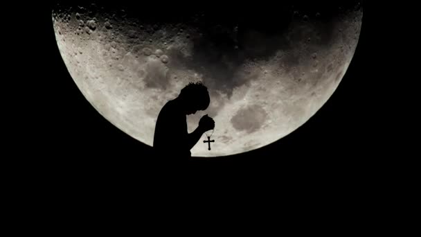 Un uomo sta pregando contro una grande luna sullo sfondo. concetto di solitudine senza speranza - Filmati, video