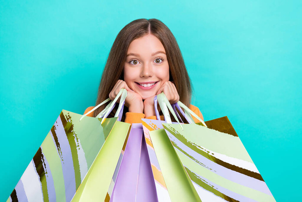 Closeup portrait photo of cute smiling good mood teen girl touch cheeks looking you hold stack bags new zara sale isolated on cyan color background. - Fotografie, Obrázek