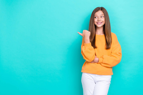 Photo of small excited girl wear orange stylish sweater white pants finger point mockup new shopping center open isolated on cyan color background. - Photo, Image