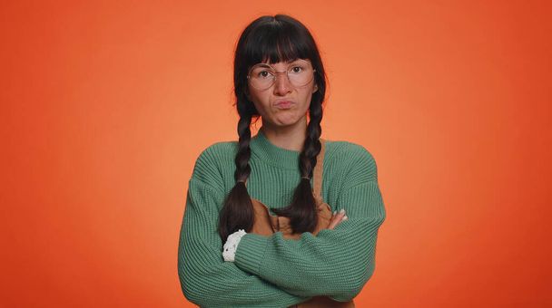 Γυναίκα σε πράσινο πουλόβερ κραυγές από τα προβλήματα έντασης άγχος αισθάνεται φρίκη απελπισία φόβο έκπληξη σοκ εκφράζει χειρονομίες οργή. Νεαρή σπασικλάκι απομονωμένη στο πορτοκαλί φόντο του στούντιο - Φωτογραφία, εικόνα