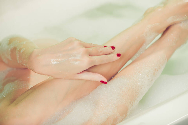 young woman hands and feet covered with foam inside white bath  - Φωτογραφία, εικόνα