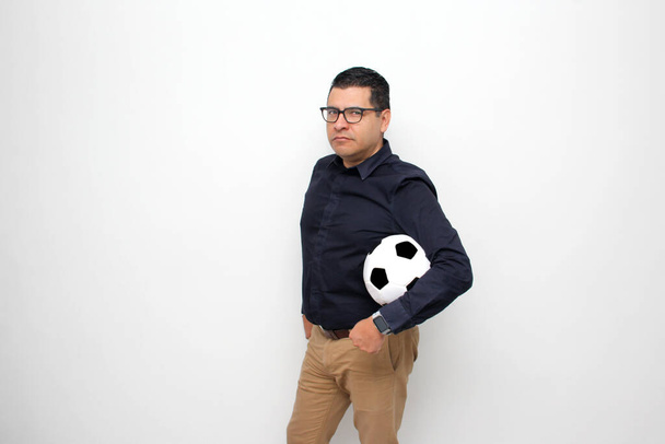 Latino adult office man plays with a soccer ball very excited that he is going to see the game and wants to see his team win - Foto, imagen