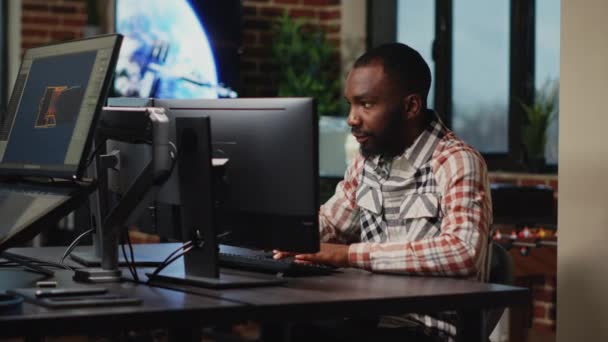 スタジオオフィスで働くアフリカ系アメリカ人男性アーティストは、ソフトウェア、デジタルスキルに関するCGIプロダクションを作成します。インフォグラフィックを開発するためにプロのインターフェイスを使用して創造的な代理店デザイナー. - 映像、動画