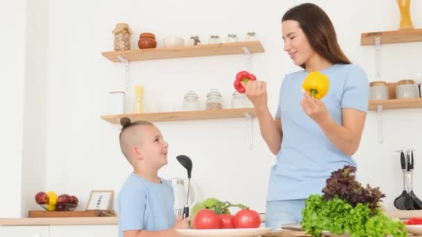 Мама и маленький сын в голубых футболках веселятся на кухне, пока готовят. Семейное время дома. - Кадры, видео