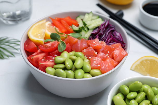 Poke bowl with salmon, edamame beans and vegetables on white table - 写真・画像