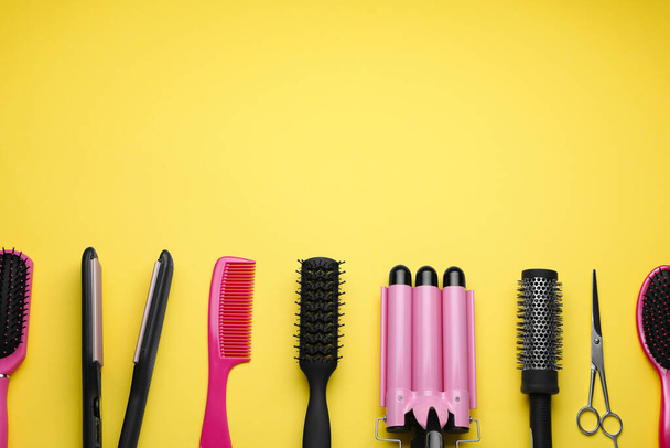 Flat lay composition of professional hairdresser tools on yellow background, space for text - Foto, Imagen