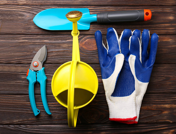 Flat lay composition with watering can and gardening tools on wooden table - Foto, Bild