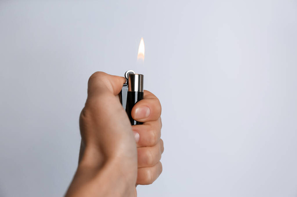 Woman holding black lighter on white background, closeup - Foto, Bild