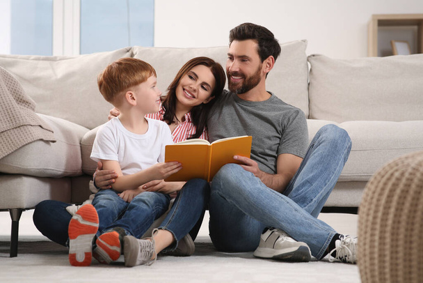 Happy parents with their child reading book on floor at home - Fotoğraf, Görsel