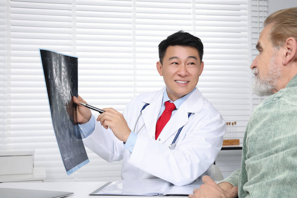 Happy doctor showing MRI images to senior patient in hospital - Foto, Bild