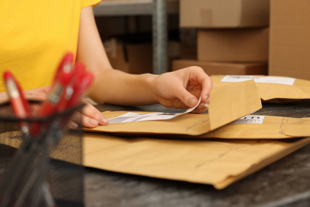 Post office worker sticking barcode on parcel at counter indoors, closeup - Foto, afbeelding