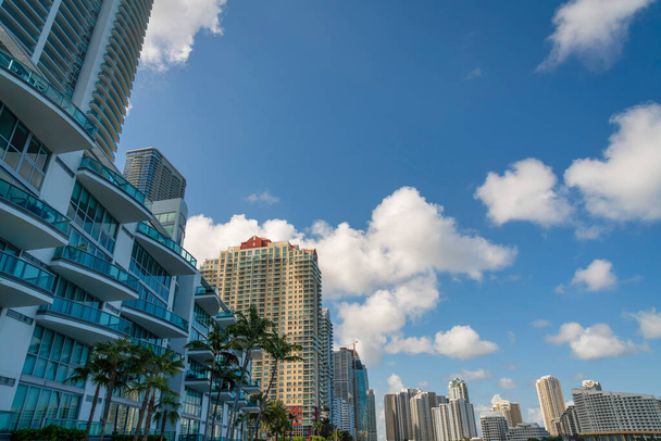 Miami, Florida cityscape with luxury condominiums against the puffy clouds in the sky- Miami, FL. There is a building at the front with glass railings on the balconies facing the palm trees outdoors. - Photo, Image