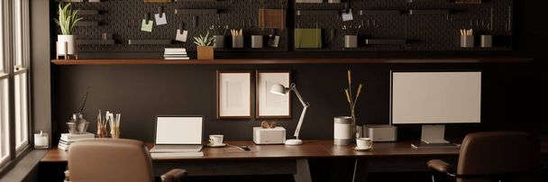 Современное рабочее место черного офиса с канцелярскими принадлежностями, ноутбуком и компьютерным макетом на столе напротив черной стены с черной пегбордом, коричневыми кожаными офисными стульями. 3D рендеринг, 3D иллюстрация - Фото, изображение