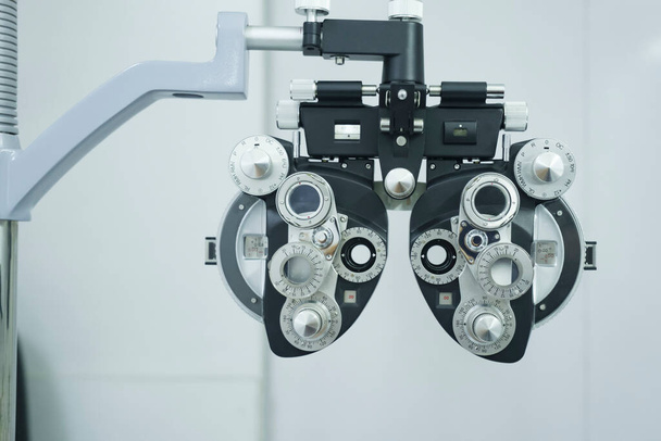 Phoropter optische klinische test machine, apparatuur, instrument in optische winkel met muur op de achtergrond gebruikt door optican voor het testen van het gezichtsvermogen van klanten, oogzorg voor het maken van nieuwe bril. - Foto, afbeelding