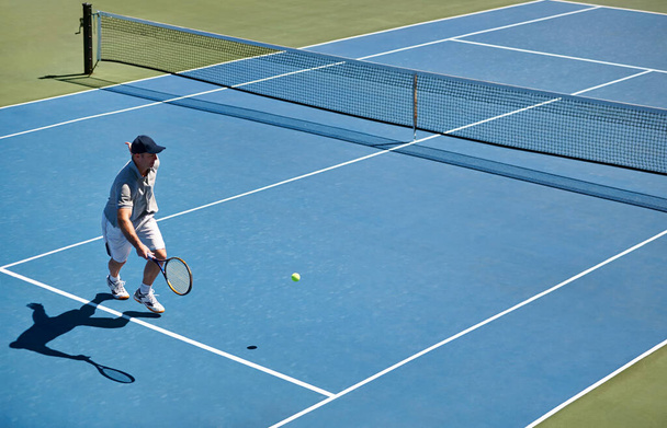 Il se montre à chaque entraînement de tennis. un homme essayant de rendre une balle sur un court de tennis - Photo, image