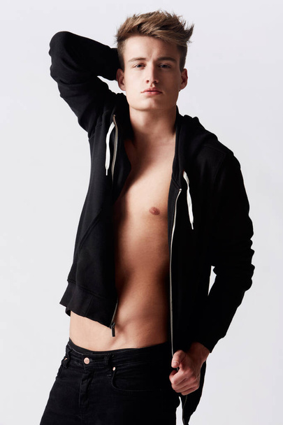 Seduction personified. Studio shot of young man wearing a hoodie over nothing - Photo, Image