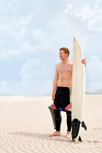 El surf es una forma de vida. Un joven surfista se prepara para ir a surfear en un caluroso día de verano - Foto, Imagen