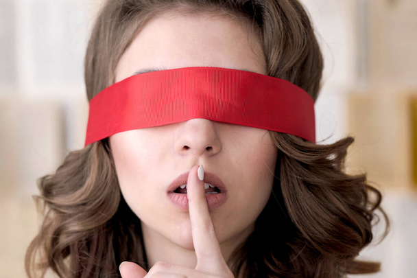 Portrait of a young beautiful brown-haired woman with long wavy hair with a red blindfold - Photo, image