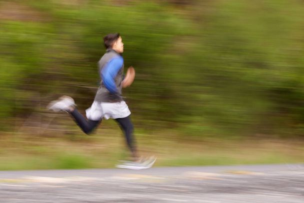 Burning up the road. Blurred image of a young man running along the road - 写真・画像