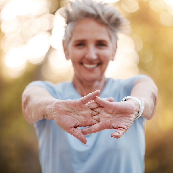Seniorenvrouw, hardloper die handen uitstrekt in het park voor hardlopen, sporten of wellness met een glimlach. Oudere vrouwelijke training, spiergezondheid en opwarmen voor training, zelfverzorging en gezonde ontwikkeling buiten. - Foto, afbeelding