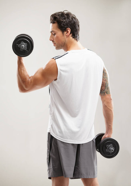 Getting in shape one rep at a time. A handsome young man doing bicep curls - 写真・画像