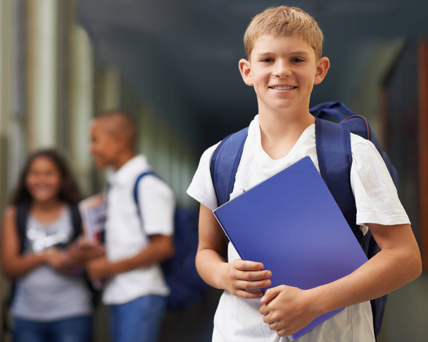 Hän on ahkera oppilas. Muotokuva onnellinen koulupoika seisoo käytävällä ystäviensä kanssa taustalla - Valokuva, kuva