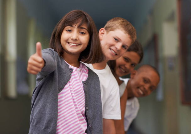 Sentirse positivo sobre la escuela. Retrato de una chica joven dándote el pulgar hacia arriba con sus amigos detrás de ella - Foto, imagen