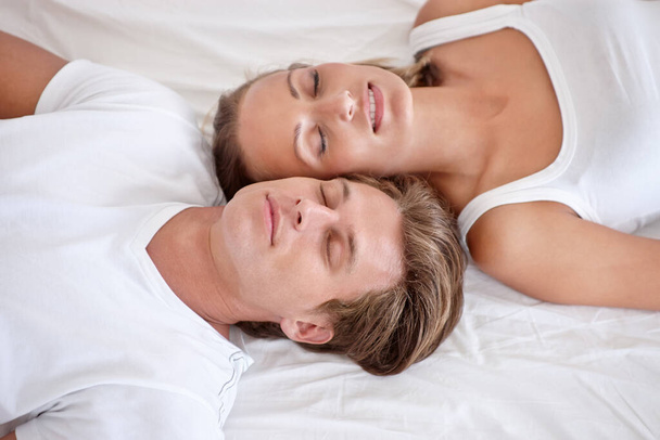 Chytám 40 mrknutí. Oříznutý pohled na mladý pár ležící v posteli a vzhlížející - Fotografie, Obrázek