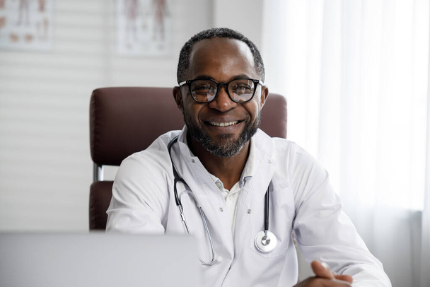 Afro-Américain médecin masculin accueille la consultation en ligne des patients dans un ordinateur portable. Un bureau offrant des services de télémédecine. médecine en ligne et concept de télémédecine - Photo, image
