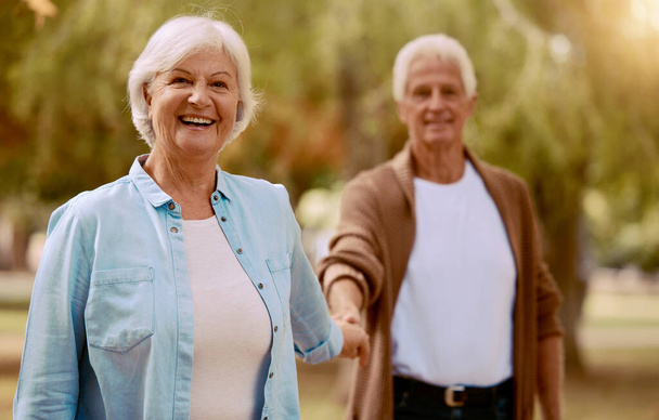 Altes Paar, Händchen haltend und Portrait in einem Park für lustige Bindung in einer natürlichen Umgebung. Liebe, Fürsorge und glückliches Rentnerehepaar in einem Naturgarten mit liebevoller Verbundenheit auf dem Land. - Foto, Bild