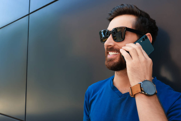 Happy man talking on phone near grey wall. Space for text - Fotografie, Obrázek