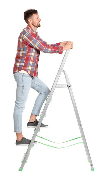 Junger schöner Mann klettert auf Metallleiter auf weißem Hintergrund - Foto, Bild