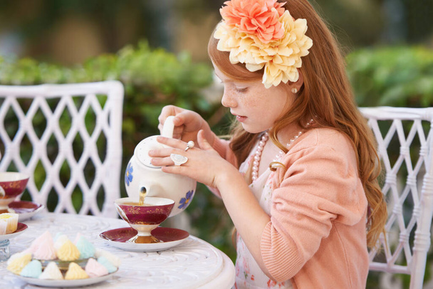 Organiser un goûter. Une mignonne petite fille ayant une partie de thé dehors - Photo, image