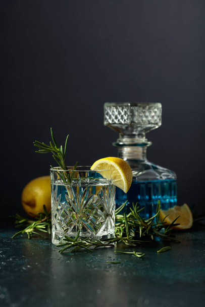 Cocktail Gin-tônico com limão e alecrim em um copo de cristal. Espaço de cópia. - Foto, Imagem