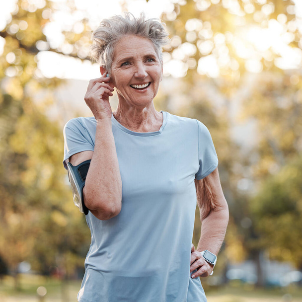 Senior woman, run outdoor and happy with music or audio podcast for lifestyle motivation, runner fitness and exercise workout. Elderly athlete, smile and training or running rest in nature park. - Foto, imagen