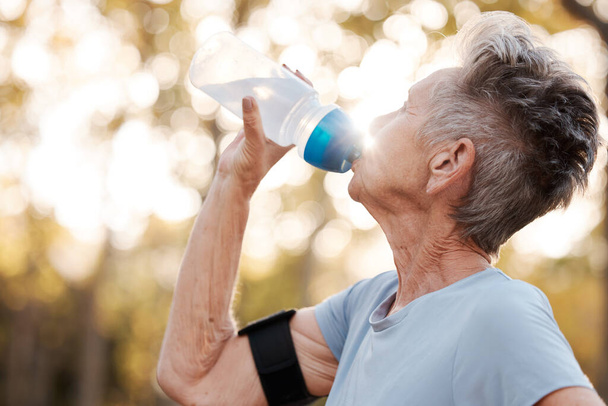 Senior woman runner, drinking water and workout in park, summer and training for health, cardio and fitness. Elderly running, exercise and hydration with water break for healthy body, mind or muscle. - Foto, Bild