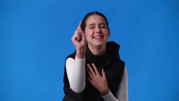 4k video of girl laughing and pointing at the camera on blue background. Concept of emotion. - Footage, Video