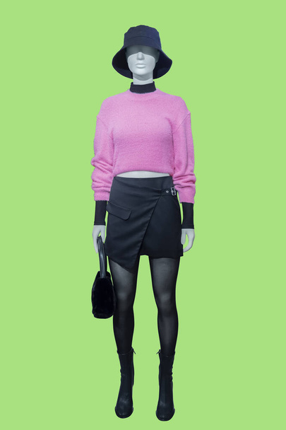 Full length image of a female display mannequin dressed in a pink sweater and black skirt isolated on a green background - Fotoğraf, Görsel