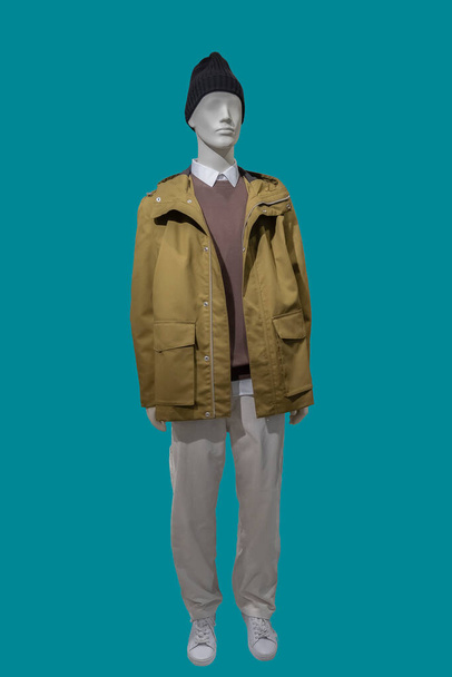 Full length image of a male display mannequin dressed in hooded jacket and corduroy light brown trousers isolated on blue background - Photo, Image