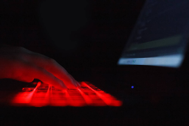 Person typing on laptop keyboard with red backlight - Photo, Image