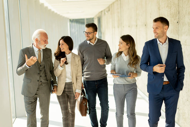 Grupo de profesionales de negocios corporativos caminando por el pasillo de oficinas en un día soleado - Foto, imagen