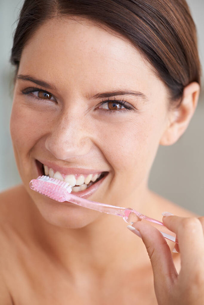 Μιλάει για την υγιεινή των δοντιών. Μια πανέμορφη νεαρή μελαχρινή βουρτσίζει τα δόντια της το πρωί. - Φωτογραφία, εικόνα