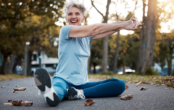 Fitness, park and stretching senior woman on ground in workout, training and energy for body wellness, outdoor healing and mental health. Elderly athlete, sports warm up and cardio exercise in nature. - Φωτογραφία, εικόνα