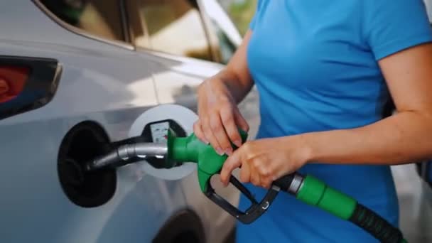 La mujer inserta una pistola de combustible en un tanque de gasolina para repostar un coche. Concepto de aumento de los precios de la gasolina, crisis del combustible - Imágenes, Vídeo