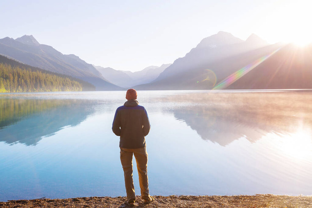Ένας άντρας ξεκουράζεται δίπλα στην ήρεμη λίμνη. Διακοπές χαλάρωσης - Φωτογραφία, εικόνα