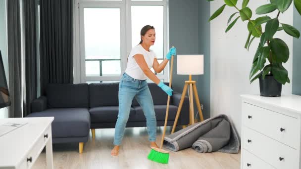 Mulher branca limpando a casa e se divertindo dançando com uma vassoura. Movimento lento - Filmagem, Vídeo