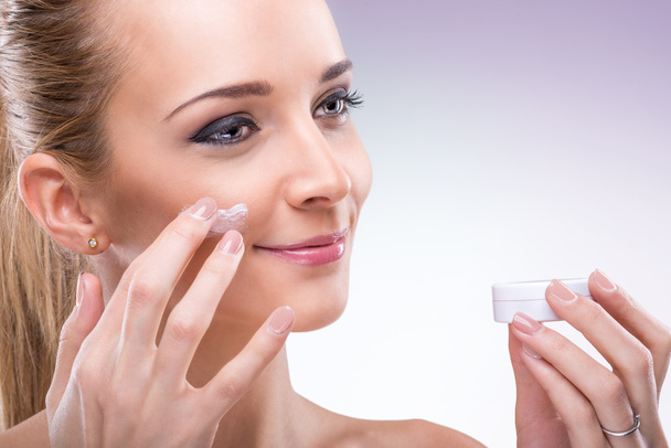 Woman applying cream on face - 写真・画像